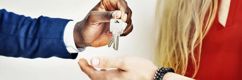 A man hands a set of keys to a home to a couple.