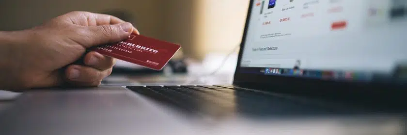 Person holding credit card in front of computer screen